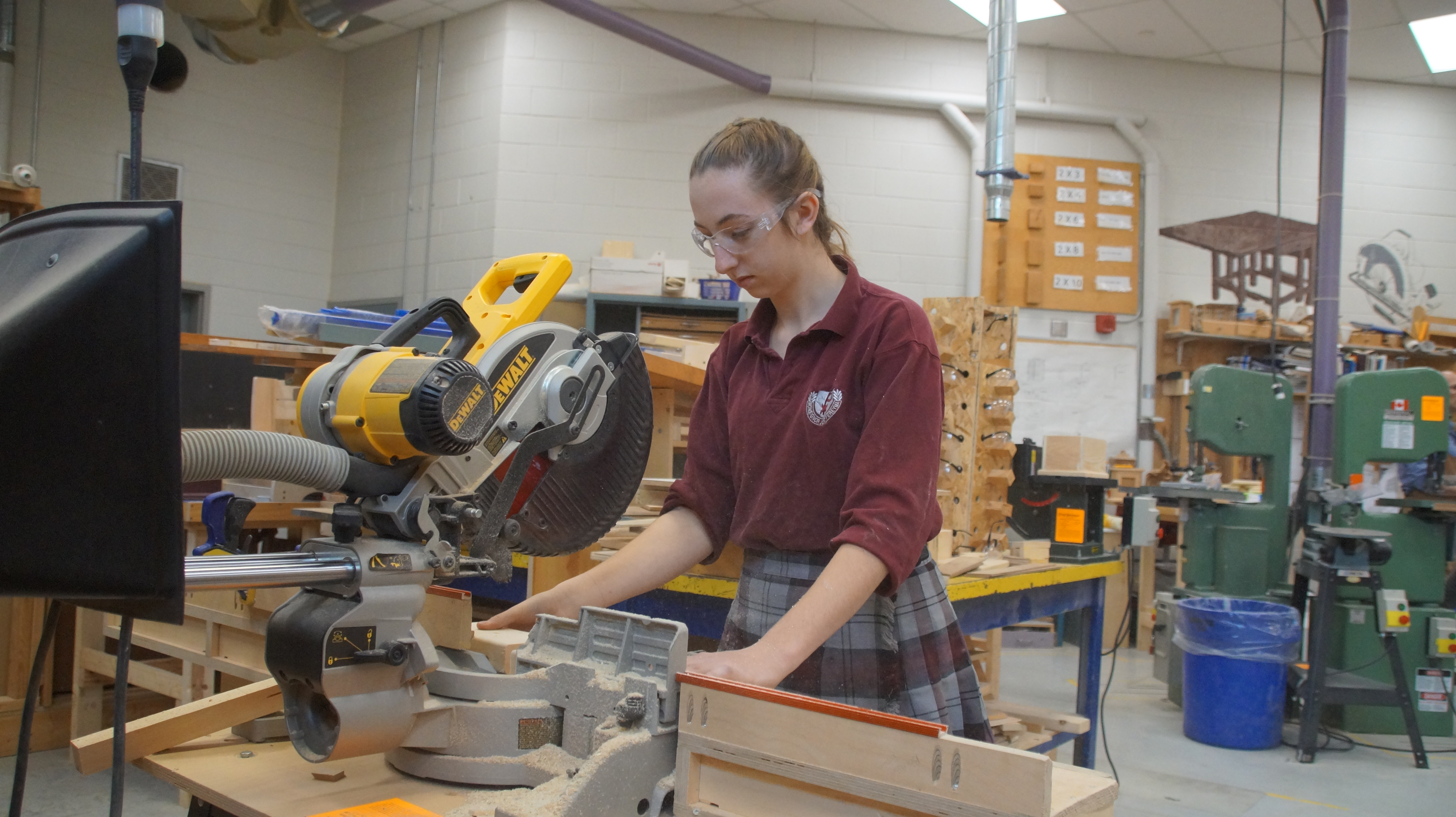Female student working with a saw in a Construction Technology classroom