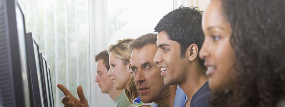 Male and female faces looking at computer screens.