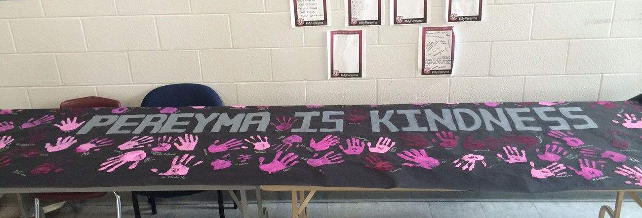 Banner saying Pereyma is Kindness on table with pink handprints on it