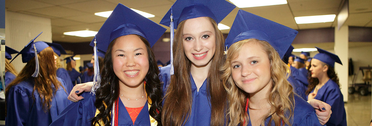 Three female students in graduation cap and gown